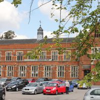 Side view of Elliott Hall Building in the background and busy carpark in the foreground.