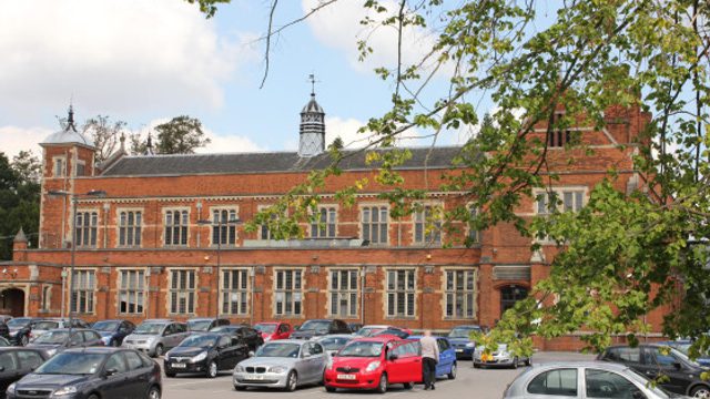 Side view of Elliott Hall Building in the background and busy carpark in the foreground.