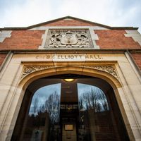 Picture of the entrance to the Elliott Hall. It has modern sliding doors that open when you approach it, dark red brick and words carved above the door reading 'THE ELLIOTT HALL'