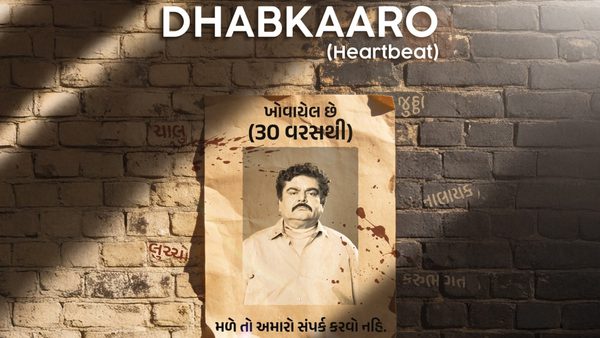 Biege brick wall with film title: Dhabkaaro, and poster of a man with dark hair and a moustache