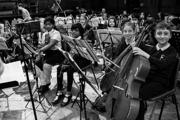 Black and White photo of children in an orchestra posing their instruments.