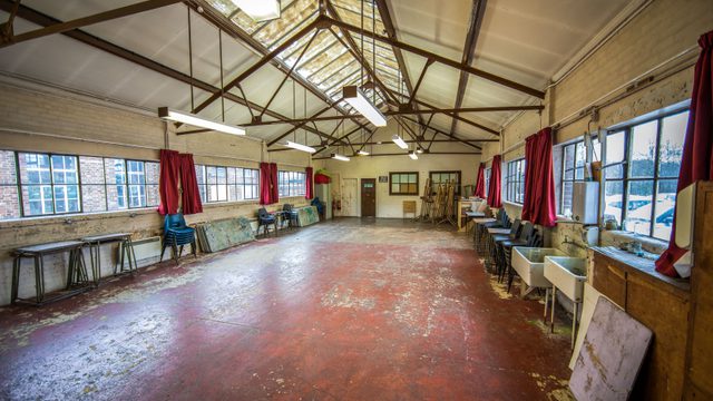 Large, long room with windows lining either side and panel lighting on ceiling