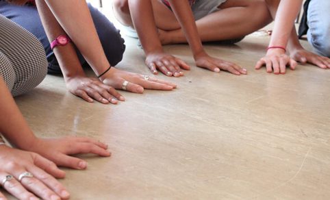 A photo of adults and childrens hands spread out on the floor.