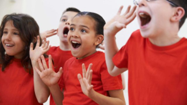 4 children in matching red t-shirts look to be smiling and happy.