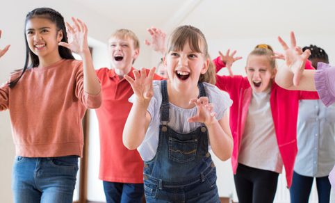 5 young girls pose with their hands up as if to be roaring at the camera.
