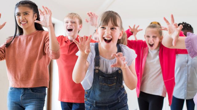 5 young girls pose with their hands up as if to be roaring at the camera.