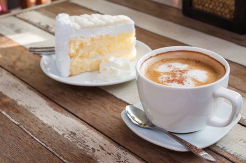 A slice of cake next to a cup of coffee