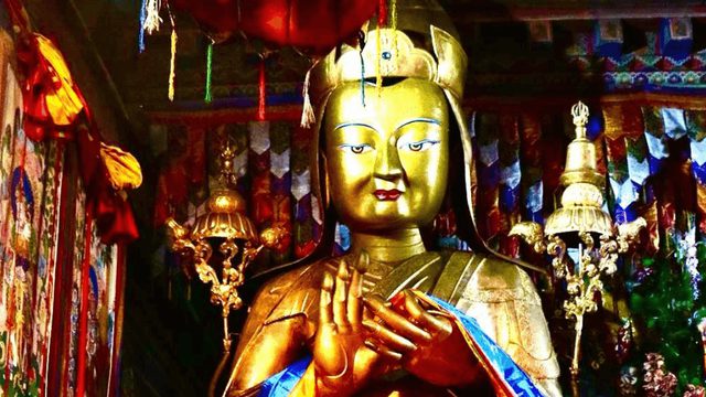 Golden statue inside a richly decorated Tibetan shrine, with the figure seated and holding hands in a ritual gesture. Colorful banners, hanging ornaments, and ceremonial objects surround the statue, representing the Lelung lineage, one of Tibet’s oldest spiritual traditions.
