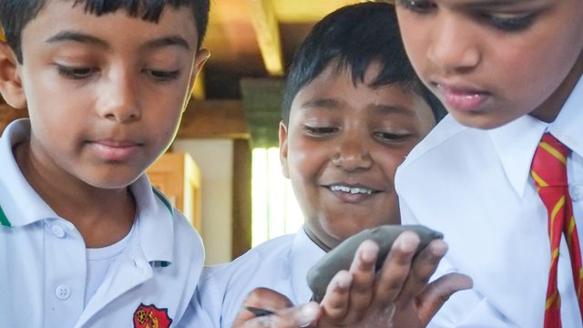 3 schoolboys look at an artifact