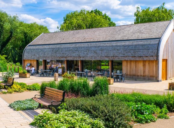One story barn building in summer, bench and bushes in the foreground