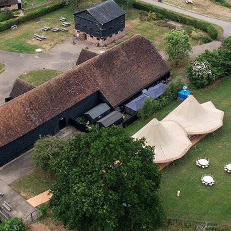 Birds Eye view/ drone image of barn with white tents set up on the field next to it