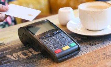 A credit card being tapped on the screen of a card reader